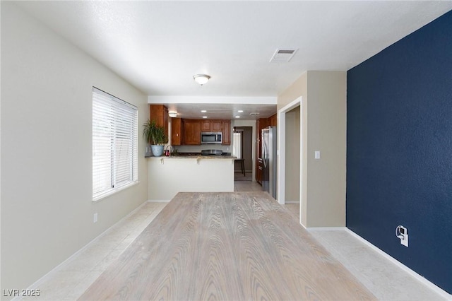 9817 Dardanelle Ct, Las Vegas, NV 89117 - kitchen featuring appliances with stainless steel finishes, a peninsula, brown cabinetry, and baseboards