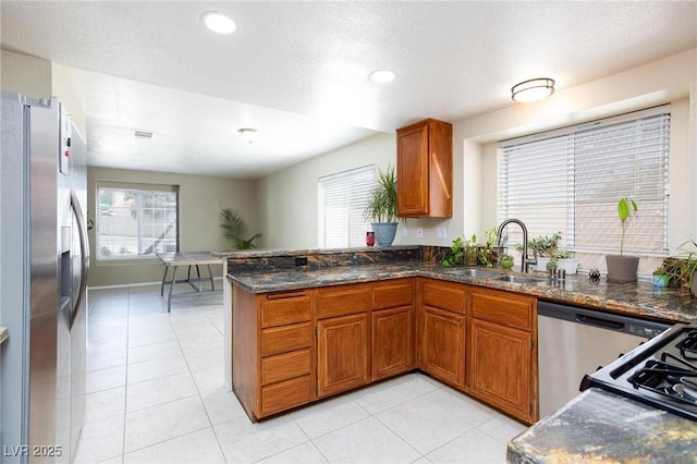 9817 Dardanelle Ct, Las Vegas, NV 89117 - kitchen with stainless steel refrigerator with ice dispenser, a sink, brown cabinetry, recessed lighting, and dark stone countertops