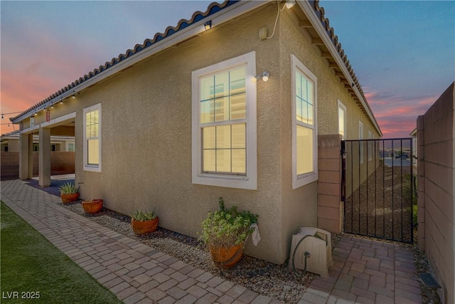 3155 Dalmazia Ave, Henderson, NV 89044 - property exterior at dusk featuring stucco siding, a gate, a tile roof, and a patio