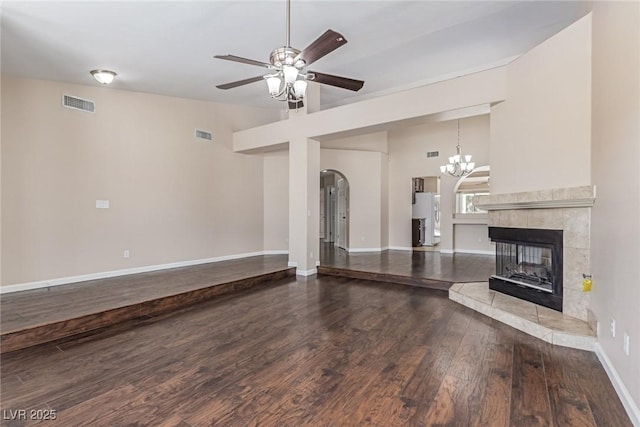 9305 Hollycrest Dr, Las Vegas, NV 89117 - unfurnished living room with wood finished floors, arched walkways, a ceiling fan, a tiled fireplace, and a chandelier