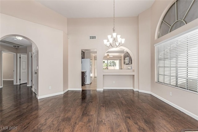 9305 Hollycrest Dr, Las Vegas, NV 89117 - unfurnished living room featuring dark wood-style floors, a chandelier, a towering ceiling, arched walkways, and baseboards