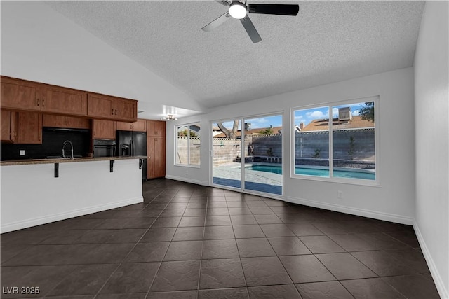 6791 Greengrove Dr, Las Vegas, NV 89103 - unfurnished living room featuring a textured ceiling, dark tile patterned floors, a sink, a ceiling fan, and lofted ceiling