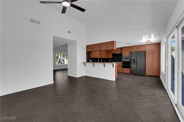6791 Greengrove Dr, Las Vegas, NV 89103 - kitchen featuring black refrigerator with ice dispenser, brown cabinets, dark tile patterned floors, a peninsula, and a kitchen bar