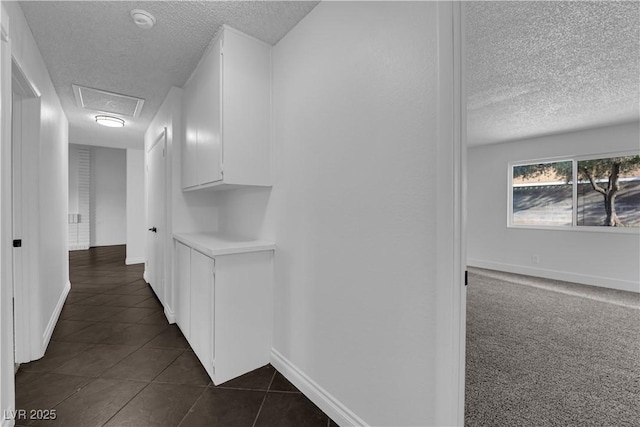 6791 Greengrove Dr, Las Vegas, NV 89103 - hall featuring a textured ceiling, dark tile patterned floors, baseboards, and attic access