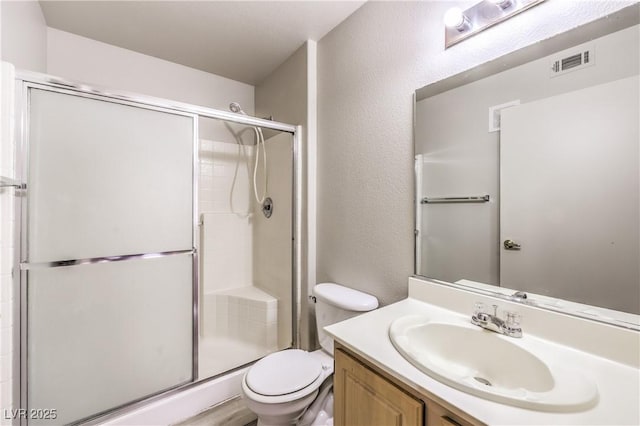 5710 E Tropicana Ave Unit 1114, Las Vegas, NV 89122 - bathroom featuring toilet, a stall shower, vanity, and a textured wall