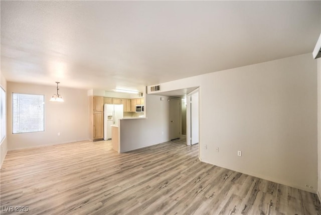 5710 E Tropicana Ave Unit 1114, Las Vegas, NV 89122 - unfurnished living room featuring light wood-style flooring, a chandelier, and baseboards