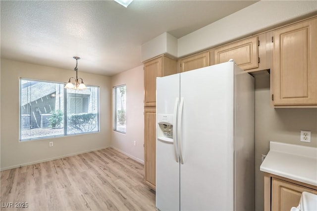 5710 E Tropicana Ave Unit 1114, Las Vegas, NV 89122 - kitchen with white fridge with ice dispenser, light brown cabinetry, light wood-style flooring, a chandelier, and light countertops