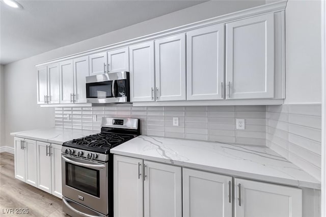 9766 Marcelline Ave, Las Vegas, NV 89148 - kitchen with stainless steel appliances, white cabinets, light wood-style flooring, and light stone countertops