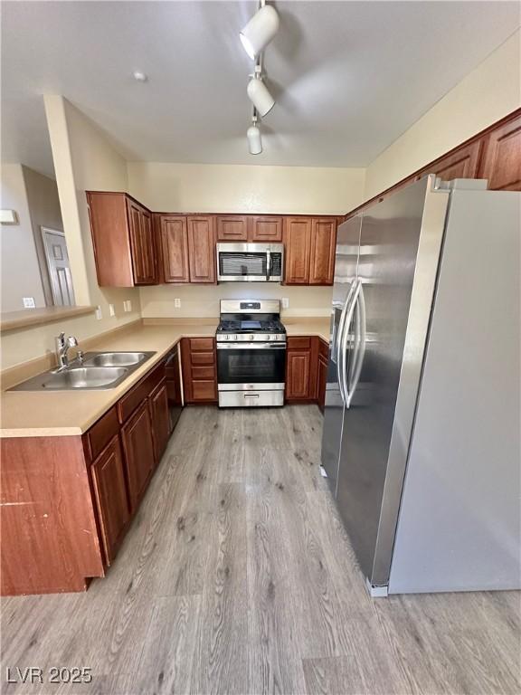 10455 Alpine Edge Ave, Las Vegas, NV 89129 - kitchen featuring stainless steel appliances, light wood-style flooring, a sink, light countertops, and brown cabinets