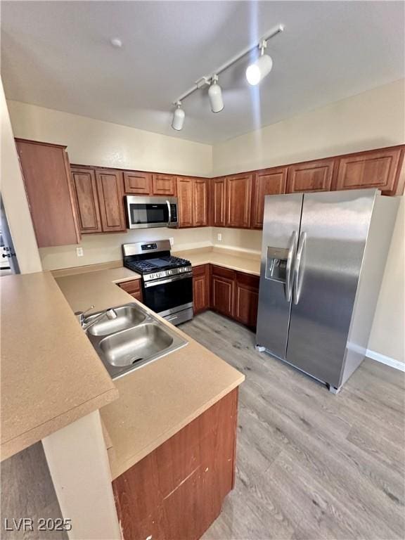 10455 Alpine Edge Ave, Las Vegas, NV 89129 - kitchen featuring appliances with stainless steel finishes, a sink, a peninsula, light wood finished floors, and light countertops