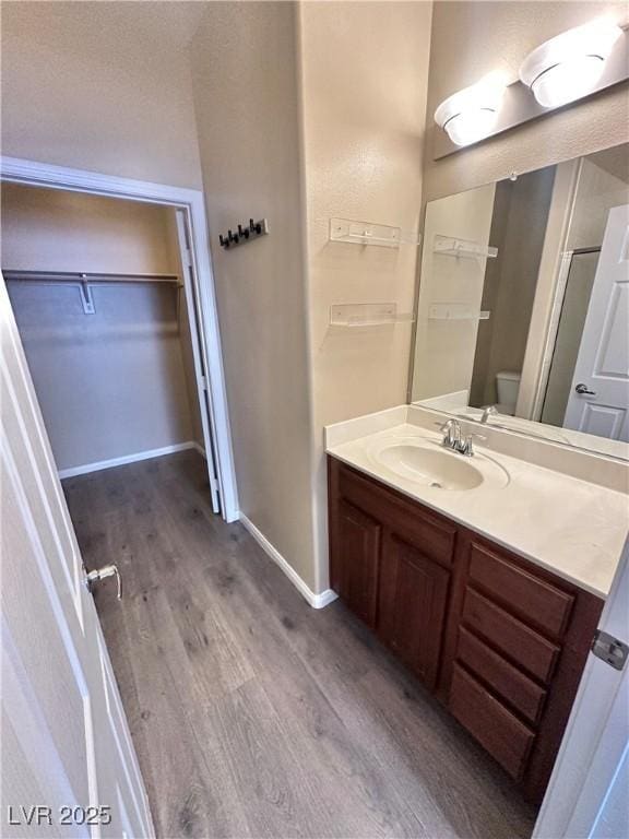 10455 Alpine Edge Ave, Las Vegas, NV 89129 - full bathroom with wood finished floors, vanity, baseboards, a walk in closet, and toilet