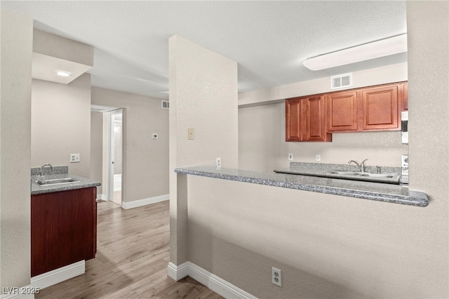 2606 S Durango Dr Unit 245, Las Vegas, NV 89117 - kitchen with a sink, light wood-style flooring, baseboards, and brown cabinetry