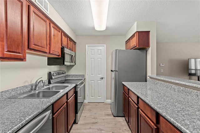 2606 S Durango Dr Unit 245, Las Vegas, NV 89117 - kitchen with stainless steel appliances, a sink, light wood-type flooring, and a textured ceiling