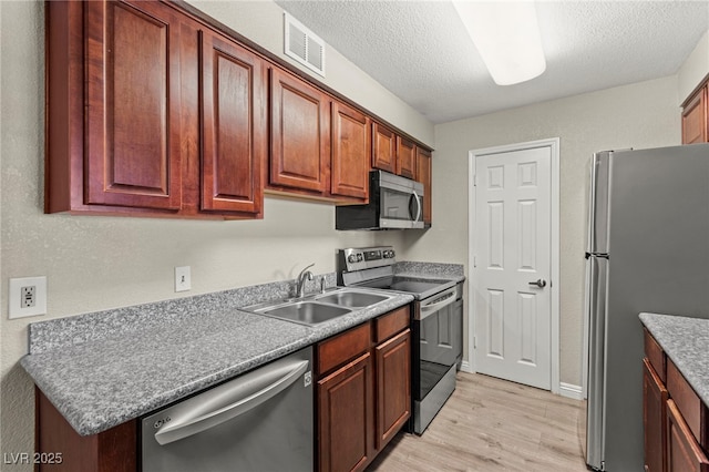 2606 S Durango Dr Unit 245, Las Vegas, NV 89117 - kitchen with stainless steel appliances, a sink, light wood finished floors, and a textured ceiling
