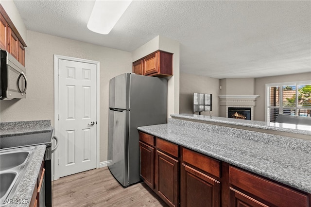 2606 S Durango Dr Unit 245, Las Vegas, NV 89117 - kitchen featuring stainless steel appliances, light wood finished floors, a fireplace, open floor plan, and a sink