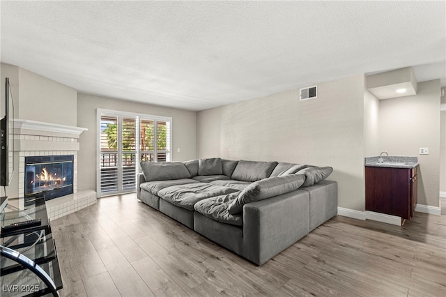 2606 S Durango Dr Unit 245, Las Vegas, NV 89117 - living room featuring wood finished floors, a brick fireplace, a textured ceiling, and baseboards