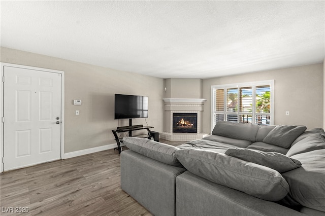 2606 S Durango Dr Unit 245, Las Vegas, NV 89117 - living room featuring wood finished floors, a brick fireplace, baseboards, and a textured ceiling