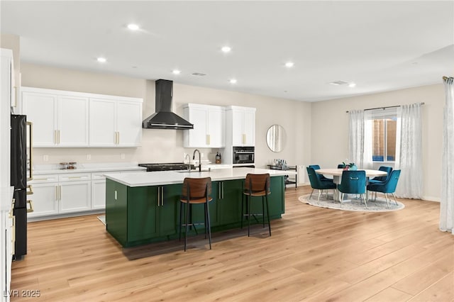 10906 Mila Landing Ave, Las Vegas, NV 89166 - kitchen with wall chimney exhaust hood, black appliances, green cabinets, light countertops, and a kitchen island with sink