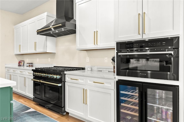 10906 Mila Landing Ave, Las Vegas, NV 89166 - kitchen featuring wall chimney range hood, beverage cooler, range with two ovens, wall oven, and light wood-style floors