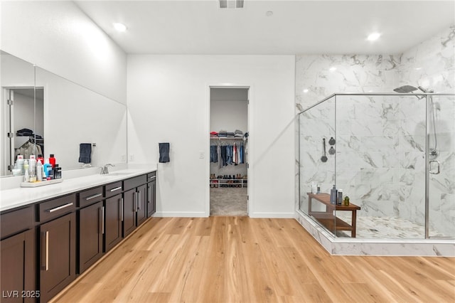 10906 Mila Landing Ave, Las Vegas, NV 89166 - bathroom featuring vanity, wood finished floors, a walk in closet, a marble finish shower, and recessed lighting