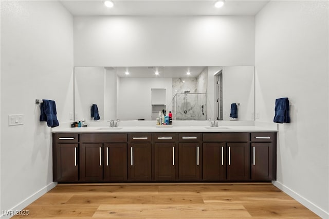 10906 Mila Landing Ave, Las Vegas, NV 89166 - bathroom featuring double vanity, baseboards, a marble finish shower, wood finished floors, and recessed lighting