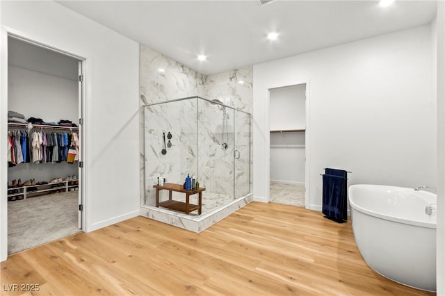 10906 Mila Landing Ave, Las Vegas, NV 89166 - bathroom with a freestanding tub, a walk in closet, a marble finish shower, wood finished floors, and recessed lighting
