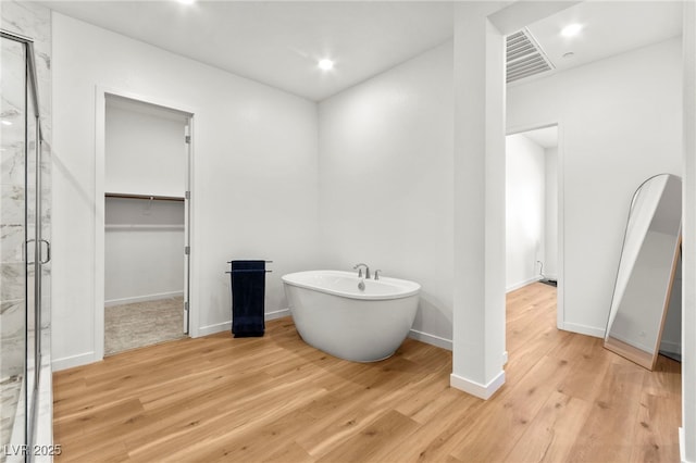 10906 Mila Landing Ave, Las Vegas, NV 89166 - full bathroom with a marble finish shower, a freestanding bath, a walk in closet, wood finished floors, and recessed lighting