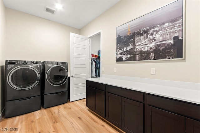 10906 Mila Landing Ave, Las Vegas, NV 89166 - laundry area with washing machine and clothes dryer, light wood-style flooring, and cabinet space