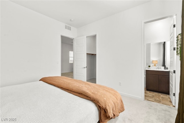 10906 Mila Landing Ave, Las Vegas, NV 89166 - bedroom with light colored carpet, baseboards, a walk in closet, a closet, and ensuite bathroom