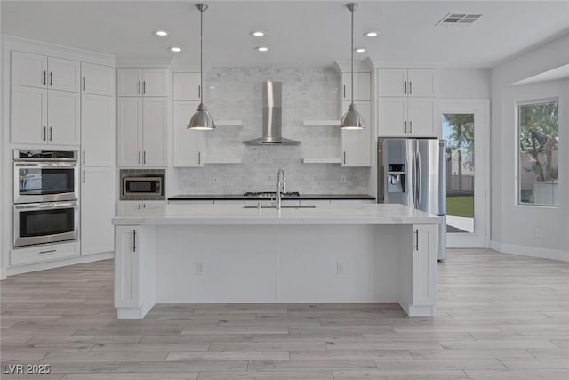 10113 Plomosa Pl, Las Vegas, NV 89134 - kitchen featuring appliances with stainless steel finishes, wall chimney range hood, a sink, light wood finished floors, and recessed lighting