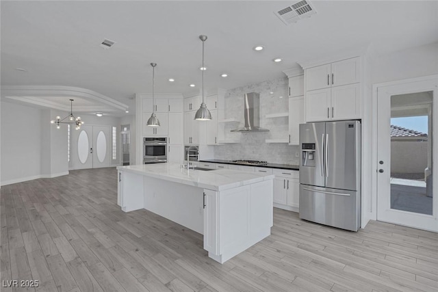 10113 Plomosa Pl, Las Vegas, NV 89134 - kitchen featuring stainless steel appliances, wall chimney exhaust hood, a sink, light wood-type flooring, and backsplash