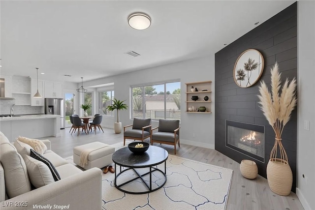 10113 Plomosa Pl, Las Vegas, NV 89134 - living room featuring baseboards, light wood-style flooring, and a large fireplace