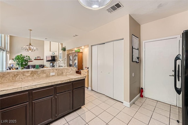 1116 Avellino Ln, Las Vegas, NV 89144 - kitchen with tile counters, dark brown cabinets, light tile patterned flooring, hanging light fixtures, and freestanding refrigerator