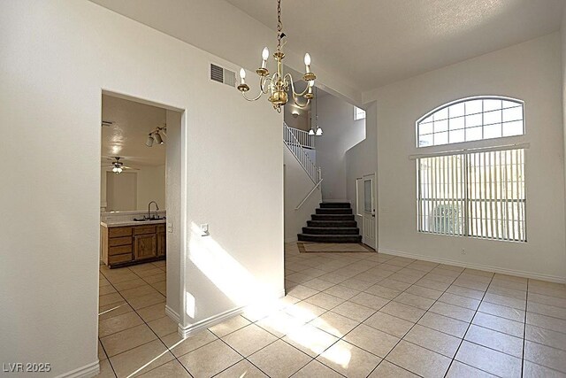 1721 Mill Canyon Dr, Las Vegas, NV 89128 - empty room with light tile patterned flooring, stairs, a chandelier, and a high ceiling