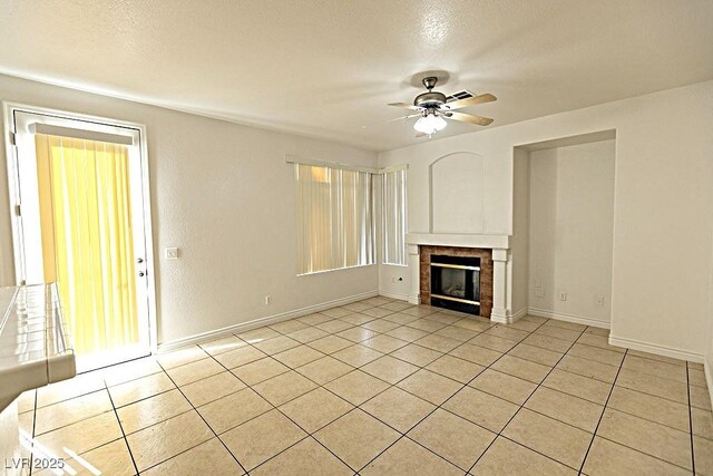 1721 Mill Canyon Dr, Las Vegas, NV 89128 - unfurnished living room featuring ceiling fan, light tile patterned flooring, a fireplace, baseboards, and a textured ceiling