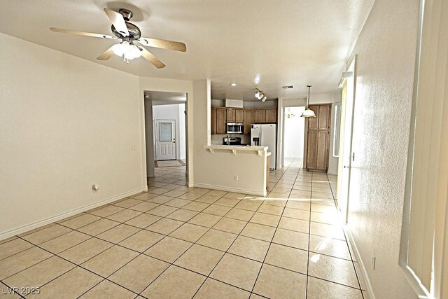 1721 Mill Canyon Dr, Las Vegas, NV 89128 - kitchen with stainless steel appliances, a peninsula, light tile patterned floors, ceiling fan, and baseboards