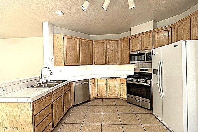 1721 Mill Canyon Dr, Las Vegas, NV 89128 - kitchen with stainless steel appliances, a sink, tile counters, a textured ceiling, and light tile patterned flooring