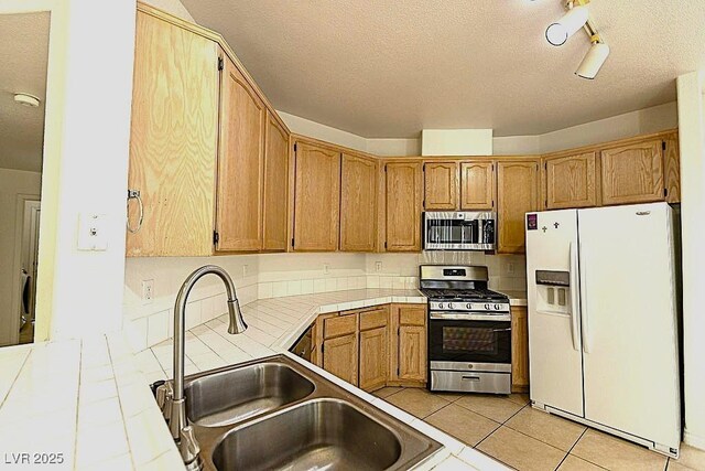 1721 Mill Canyon Dr, Las Vegas, NV 89128 - kitchen with stainless steel appliances, tile counters, a sink, a textured ceiling, and light tile patterned flooring