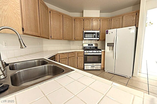 1721 Mill Canyon Dr, Las Vegas, NV 89128 - kitchen featuring stainless steel appliances, a sink, tile countertops, tile patterned floors, and brown cabinetry