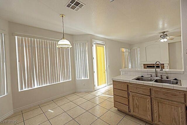1721 Mill Canyon Dr, Las Vegas, NV 89128 - kitchen with a sink, tile counters, a ceiling fan, light tile patterned floors, and baseboards