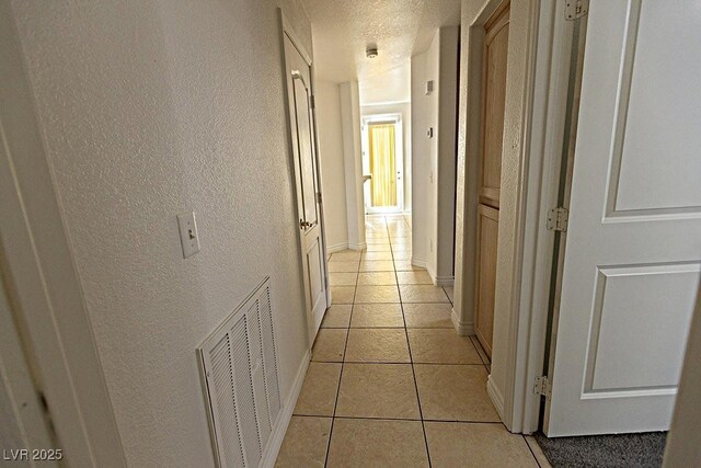 1721 Mill Canyon Dr, Las Vegas, NV 89128 - hall featuring a textured wall, light tile patterned floors, baseboards, and a textured ceiling