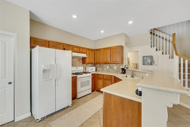 1101 Elation Ln Unit 2, Henderson, NV 89002 - kitchen with white appliances, a peninsula, under cabinet range hood, a sink, and light tile patterned flooring