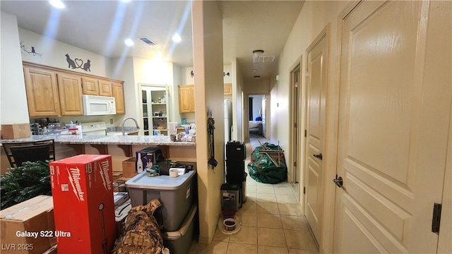 864 Chianti Way, Mesquite, NV 89027 - kitchen with white microwave, light tile patterned floors, light brown cabinets, a breakfast bar, and light stone countertops