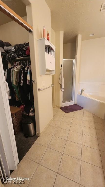 864 Chianti Way, Mesquite, NV 89027 - full bath featuring tile patterned flooring, a shower stall, a garden tub, a walk in closet, and a textured ceiling