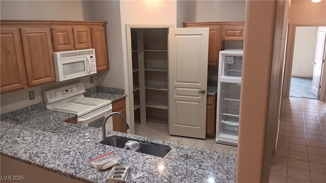 864 Chianti Way, Mesquite, NV 89027 - kitchen featuring white appliances, a sink, light tile patterned floors, stone countertops, and brown cabinets