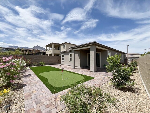 12565 Huckleberry Oak Ave, Las Vegas, NV 89138 - rear view of property featuring a putting green, a patio, stucco siding, and a fenced backyard
