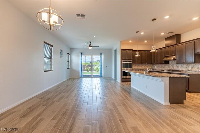 12565 Huckleberry Oak Ave, Las Vegas, NV 89138 - kitchen with double oven, under cabinet range hood, a sink, dark brown cabinetry, and a ceiling fan