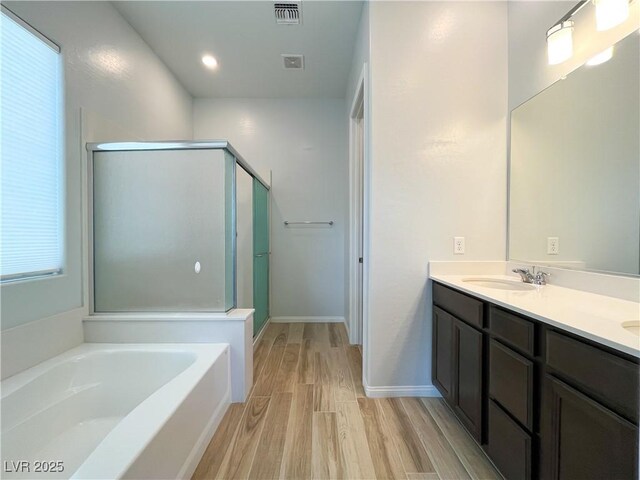 12565 Huckleberry Oak Ave, Las Vegas, NV 89138 - bathroom featuring wood finished floors, a garden tub, double vanity, a shower stall, and baseboards
