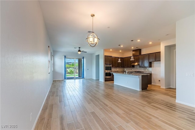 12565 Huckleberry Oak Ave, Las Vegas, NV 89138 - kitchen featuring open floor plan, dark brown cabinetry, a chandelier, light wood finished floors, and double oven
