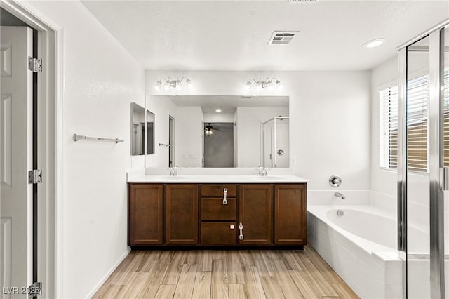 7189 Ashcroft St, North Las Vegas, NV 89084 - full bath with ceiling fan, a bath, double vanity, a stall shower, and wood finished floors